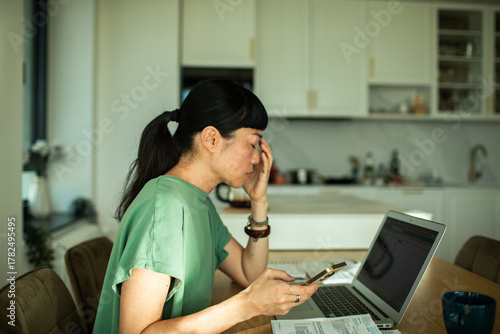 Young adult woman stressed over finances at home kitchen