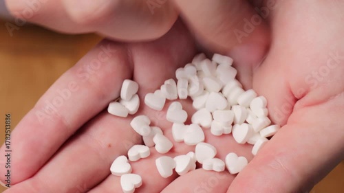 Hand gently holding small love-shaped tablets, love image showing trust, health, and compassion, love moment perfect for pharmaceutical or healthcare themed footage.