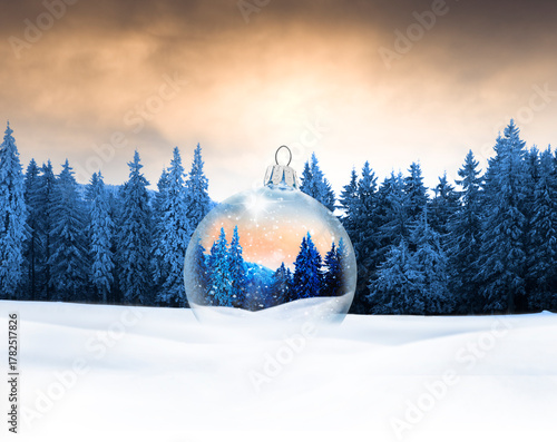 Gläserne WEihnachtskugel mit Wintermotiv in einer Bewaldeten Schneelandschaft