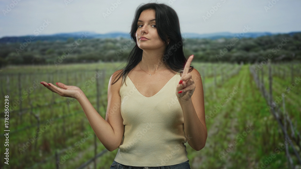 Fototapeta premium Young woman wearing a sleeveless top pointing finger and open palm in a forest clearing under natural light; serenity.