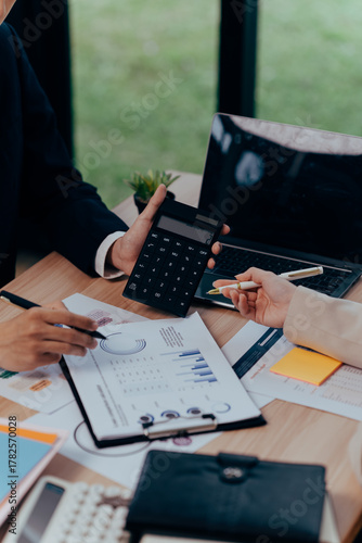 Navigating Numbers: A focused view on business professionals collaborating, scrutinizing financial reports, and crunching numbers with tools of the trade.