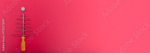 Fotografie Screws and screwdriver arranged as christmas tree on pink background