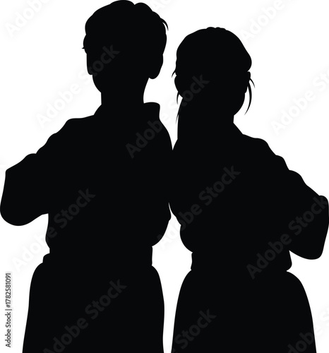 Silhouette of two children standing back to back wearing martial arts uniforms with arms crossed