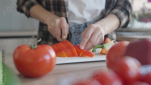 Woman Slicing Red Bell Pepper On Wooden Cutting Board In Kitchen