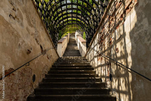 Prague, Czech Republic – August 6, 2025: Stone steps of Plečnik’s Bulls’ Staircase in Prague Castle garden, Czech Republic, with historic rampart walls and archway, on a summer afternoon.