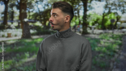 Man with pursed lips looks sideways amidst sunlit trees and green foliage casting dappled shadows in forest; curiosity.