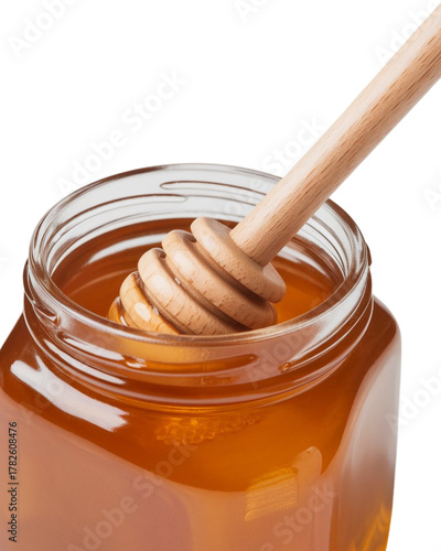 Golden, sweet honey dripping from a wooden dipper into a clear glass jar ready for breakfast