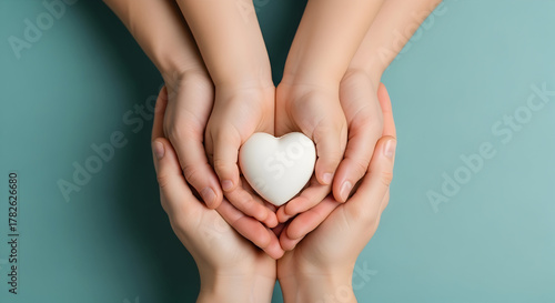 Family holding a white heart in their hands on a blue background, love and care concept