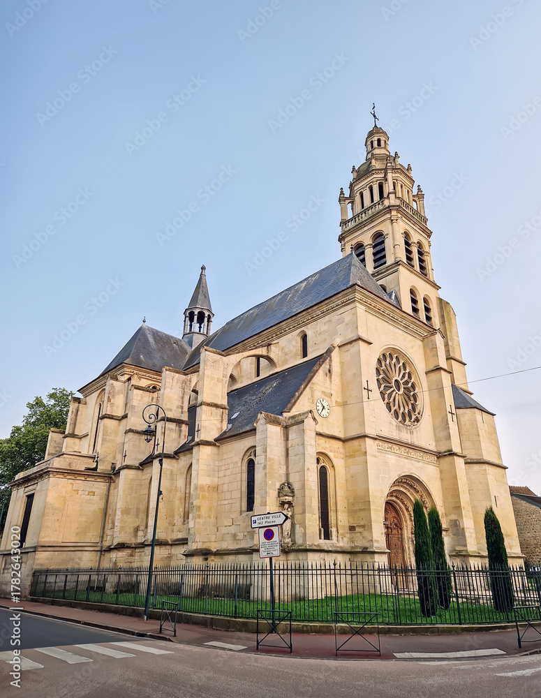 Obraz premium The historic Church Eglise Saint-Martin de L'Isle-Adam in France. Impressive stone architecture, tall bell tower, and prominent rose window