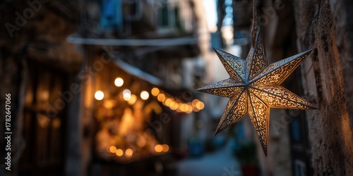 Fototapeta Naklejka Na Ścianę i Meble -  Bethlehem star decoration hangs on a lit street in a southern European town with stone buildings and holiday lights. Christmas atmosphere in a warm historic setting with festive decor.