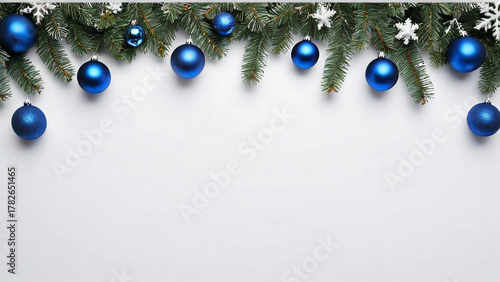 Weihnachtsgirlande aus Tannenzweigen und blauen Christbaumkugeln mit Schneeflocken auf weißem Hintergrund