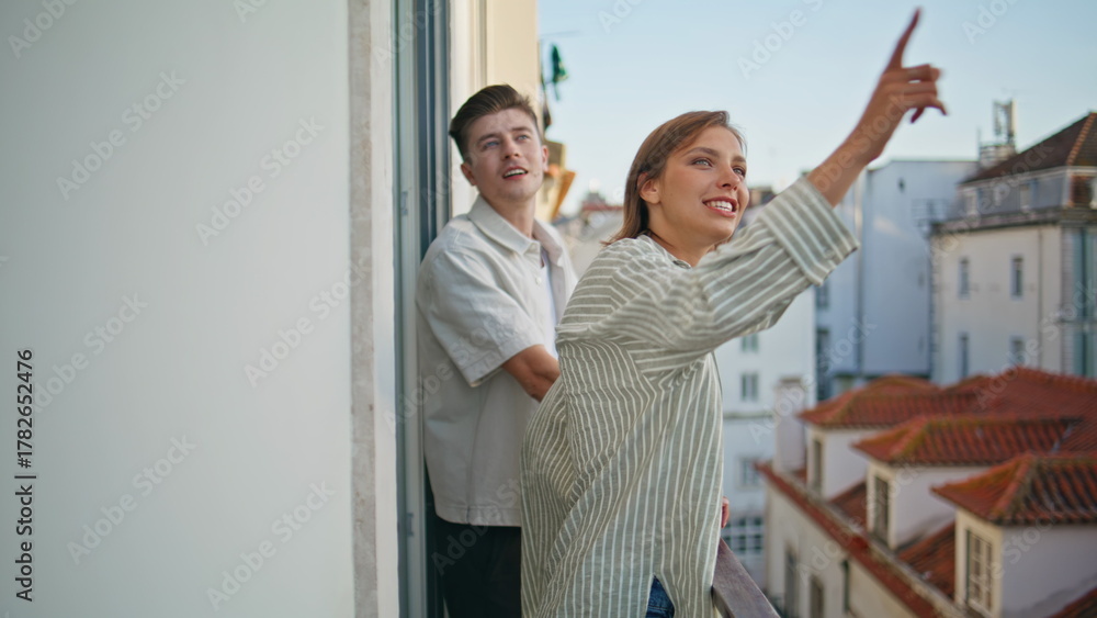 Obraz premium Happy sweethearts looking distance standing terrace. Excited woman pointing