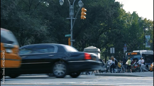 Busy New York City scene with yellow taxis and people crossing the street at Columbus Circle near Central Park.