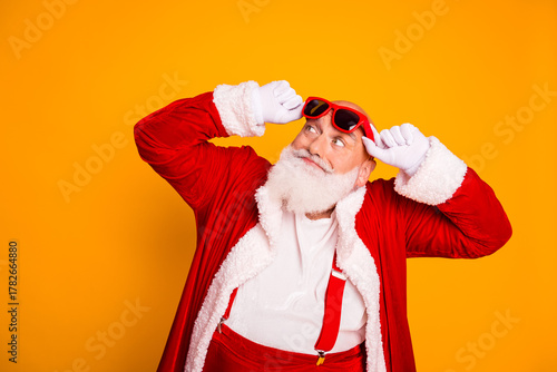 Fototapeta Santa in a red suit with white fur celebrates the holidays with a playful yellow