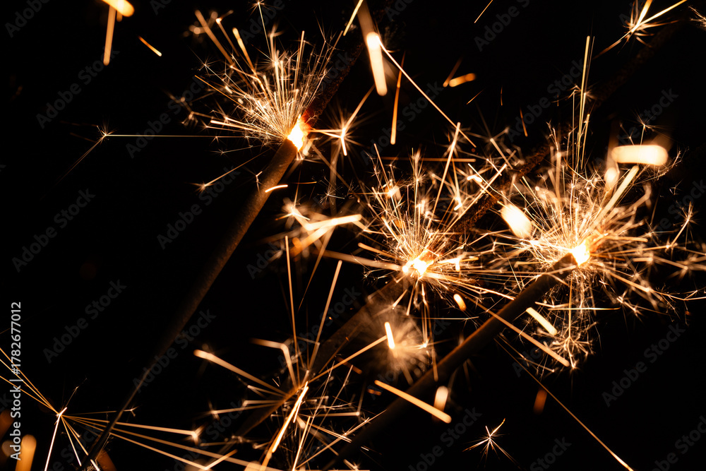 Obraz premium Bright Sparklers Burning on Pure Black Background