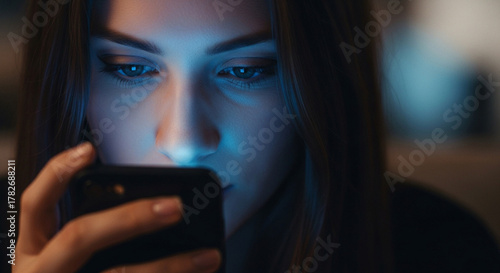 Woman Engrossed in Smartphone's Glowing Screen at Night