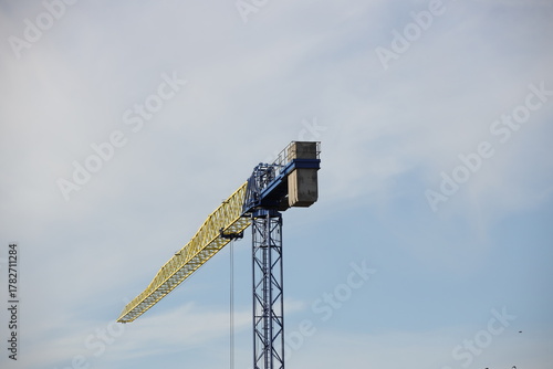 Tower cranes work during the construction of a multi-story building. New apartments for residents and premises for offices. Risky work at height. Lifting heavy building materials. City development
