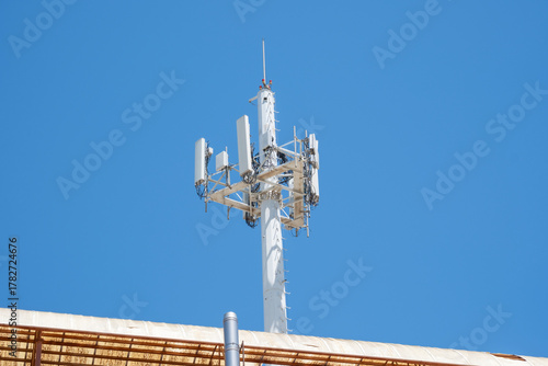 Obraz na plátně Cellular communication tower against clear blue sky on rooftop