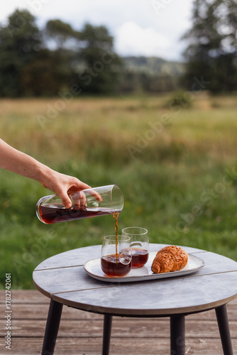 Enjoying coffee and croissants on a wooden terrace in a country garden