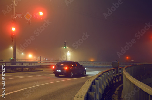 Lone car at a city intersection at night in foggy winter weather
