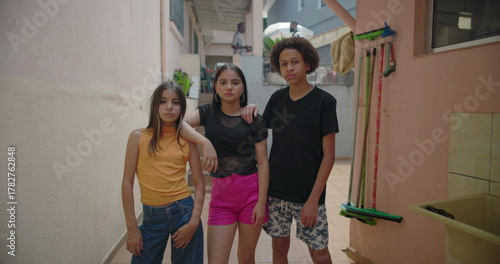 Teenagers posing with serious expressions in suburban alleyway, showing strength, resilience, and determination, multicultural group in an urban setting