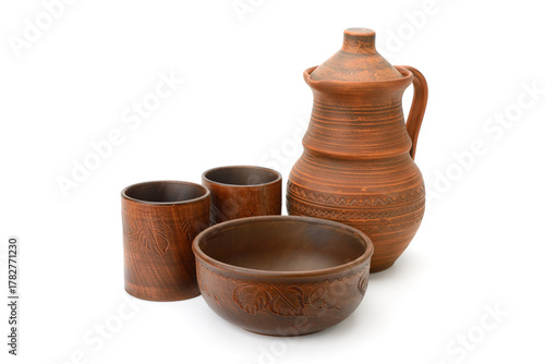 Set of traditional earthenware pottery including jug, cups, and bowl made of brown clay with carved patterns isolated on white background