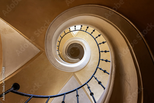 A captivating view of a spiral staircase, photographed from the bottom looking up to the top. The intricate design and elegant curves create a mesmerizing and dynamic visual effect.