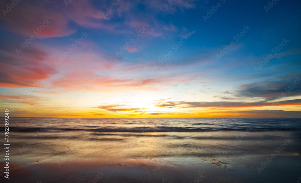 Obraz premium serene panorama image capture beauty sunset over calm ocean. sun low on horizon casting warm golden glow across sky and reflect off gentle wave. warm orange near creating peaceful calm atmosphere.