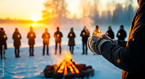 Close up of Hands Holding Lit Candle,  People Standing Around Fire In Winter Forest with Low Sun in Blurred Background