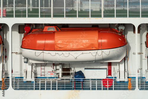 Tableau sur toile Enclosed orange and white lifeboat mounted on the side of a cruise ship