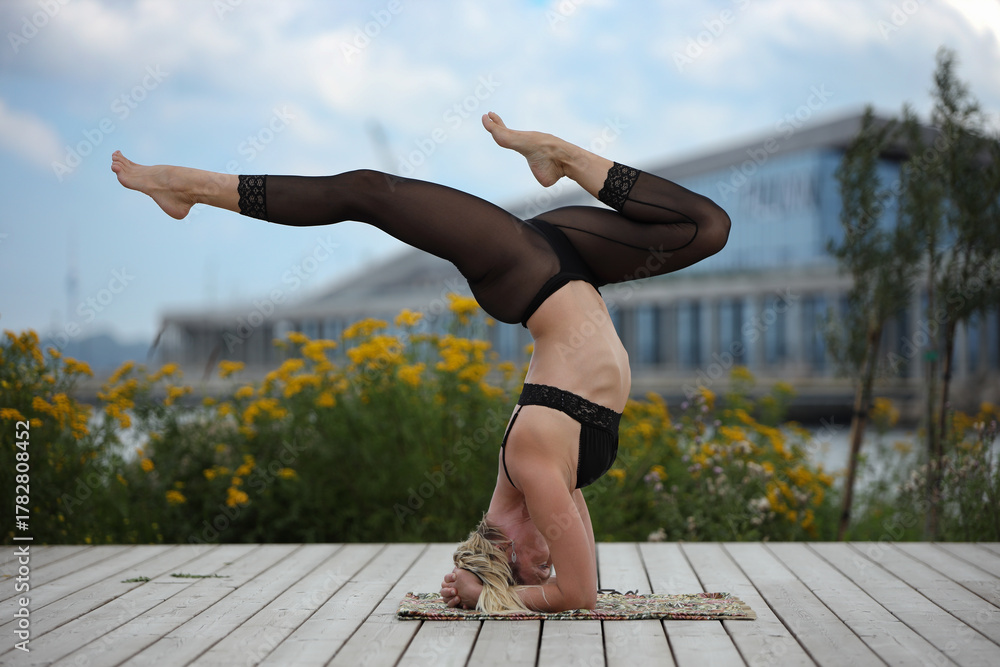 Fototapeta premium Young Woman Practicing Yoga Headstand Outdoors on Deck