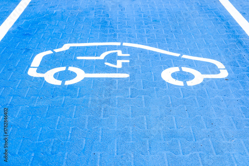 car silhouette on blue background, EV charging station parking, public space, electric vehicle infrastructure, green transport, eco-friendly, parking lot, electric mobility, zero emission