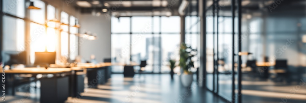 Fototapeta premium Blurred Interior of a Modern Open Plan Office with Natural Light and Glass Partitions