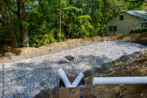 Home septic system leach field in progress with crushed stone layer, and the distribution box waiting for the input pipe
