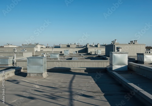Architectural perspective showcasing multiple layered rooftops, varied materials, vents, and shadow lines on structures reaching towards the horizon, construction, expanse, roof