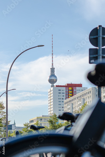 Berlin's street view with city bikes parking, residential buildings along the road and famous TV tower
