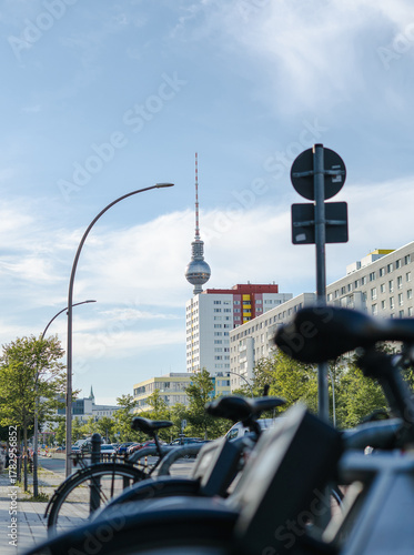 Berlin's street view with city bikes parking, residential buildings along the road and famous TV tower