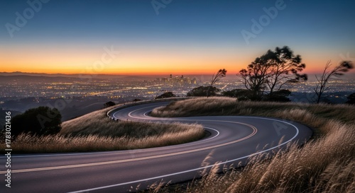 Serpentine road leading to illuminated cityscape under twilight horizon scenery