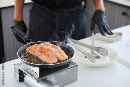 chef cooking salmon steaks in the kitchen