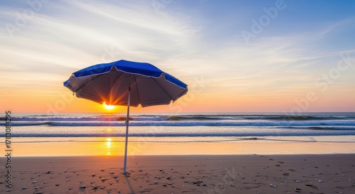 Fototapeta Naklejka Na Ścianę i Meble -  Beach Umbrella at Sunset: A solitary beach umbrella stands sentinel against a vibrant sunset over the ocean. It captures the essence of summer, offering a moment of tranquility and beauty by the sea.