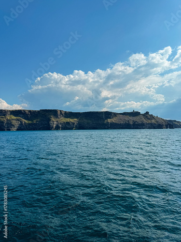 Coastal cliffs with deep blue sea under clear sky and clouds