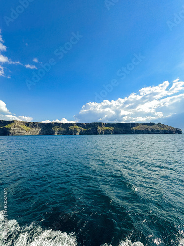 Coastal cliffs with deep blue sea under clear sky and clouds