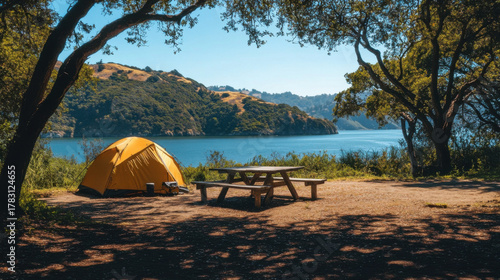 Serene campsite with yellow tent and picnic table overlooking a calm lake