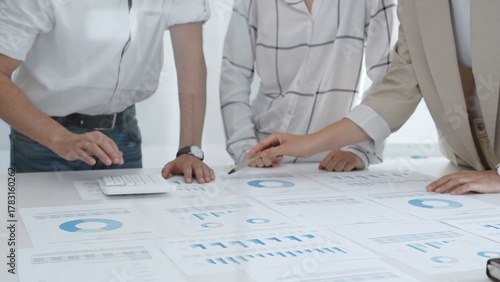 Professional team reviewing financial charts and graphs, working together in modern office space, developing strategic improvements. Business people concept