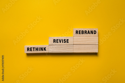Photos rethink revise and rebrand words on wooden blocks isolated on yellow background