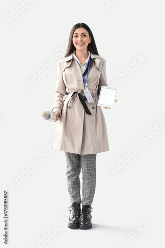 Female journalist with blank tablet computer and microphone on light background