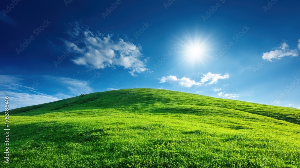 Fototapeta premium Bright Green Hill Under Clear Blue Sky with Sunlight and Wispy Clouds, Ideal for Nature and Landscape Themes in Photography and Design