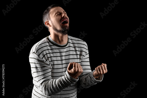 Screaming young man on blac...