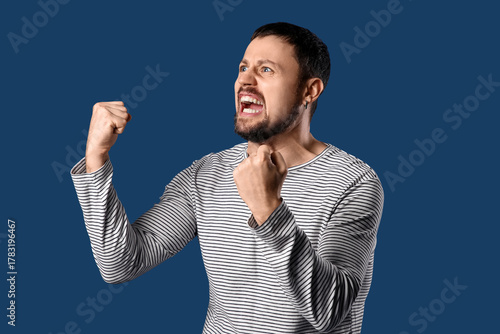 Screaming young man on dark...