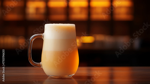 Frosty glass jug filled with cold beer on wooden bar counter, warm ambient lighting